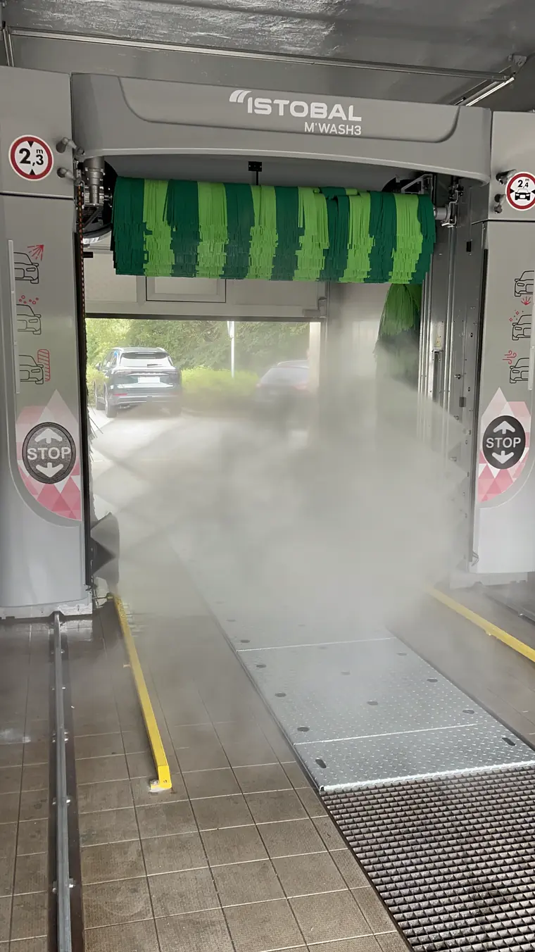 Portálová mycí linka ISTOBAL M’WASH3 se zelenými kartáči v chodu, v hale je vidět nástřik vody