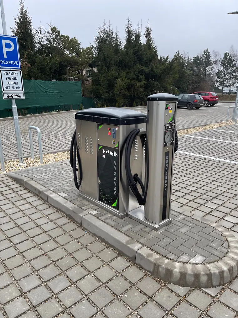 Samoobslužný vysavač AD Produzione a sloup s kompresorem na dlážděném ostrůvku u parkoviště